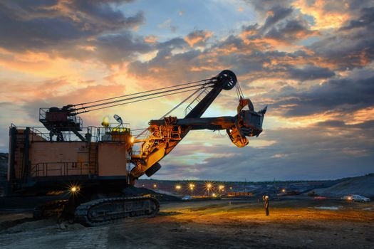 Gestión de Controversias en Contratos Mineros: Cómo Evitar que un Desacuerdo Paralice su Producción A powerful excavator dominates the landscape during a dramatic sunset, highlighting industrial activity.